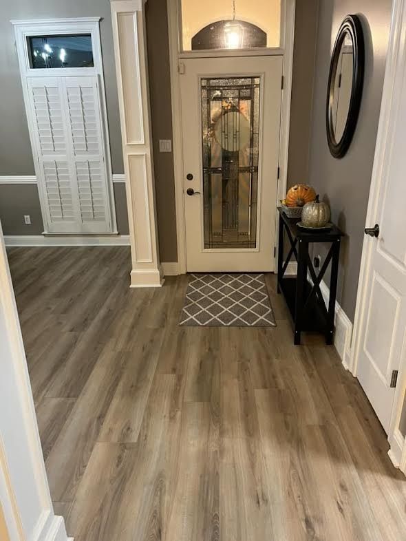 A hallway with hardwood floors and a glass door.