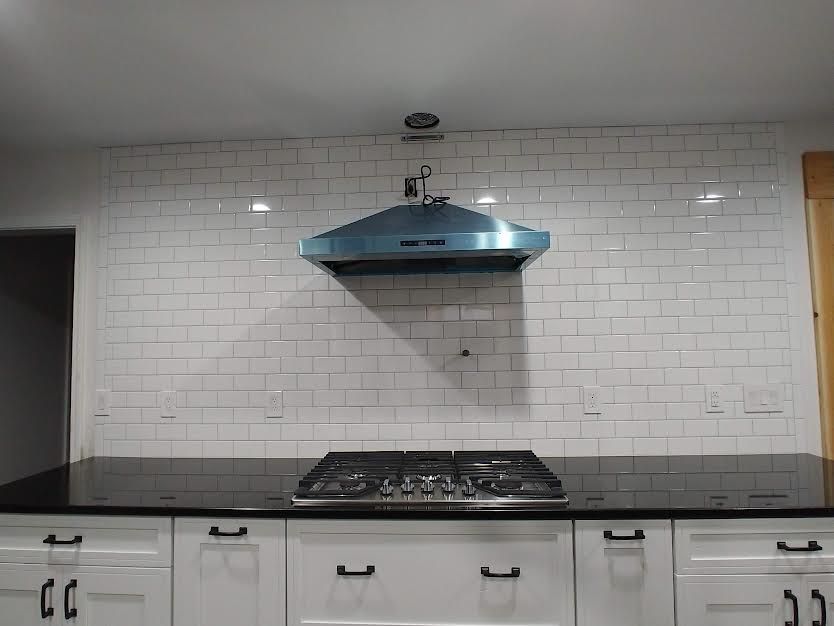 A kitchen with a stove top oven and a hood above it.