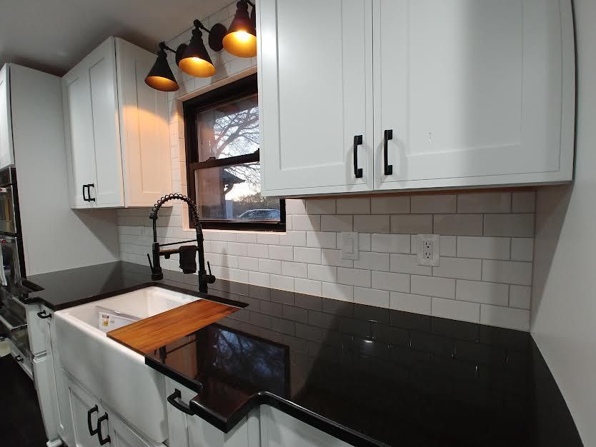 A kitchen with white cabinets and black counter tops