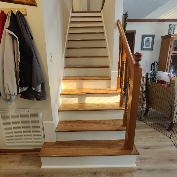 A wooden staircase with white steps and a wooden railing