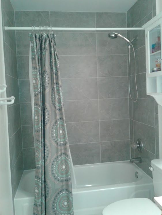 A bathroom with a bathtub , toilet , shower and shower curtain.