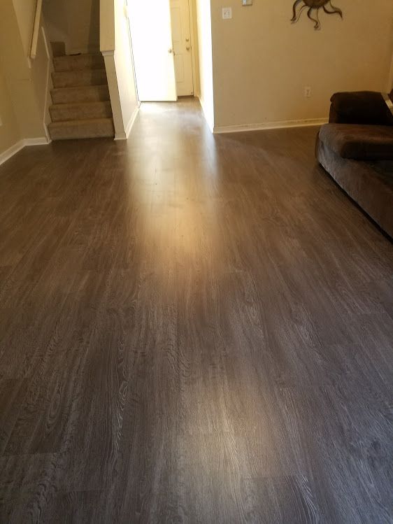 A living room with hardwood floors , a couch , and stairs.