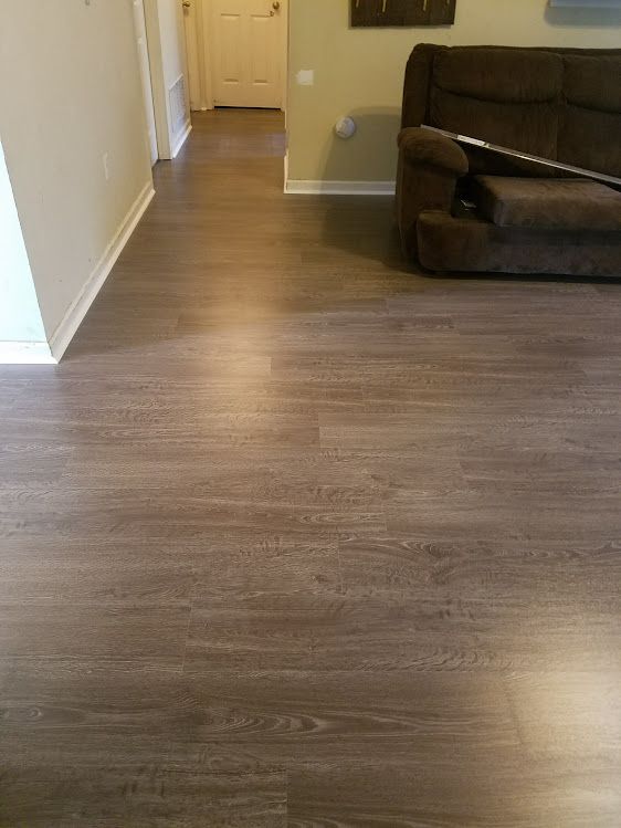 A living room with hardwood floors and a couch and chair.