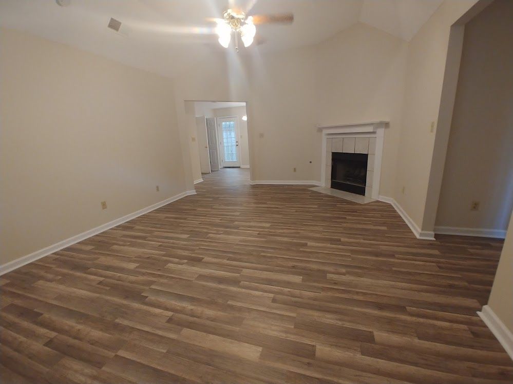 An empty living room with hardwood floors and a fireplace.