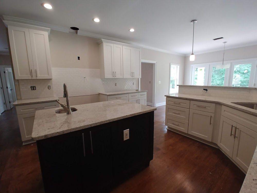 A kitchen with white cabinets and a large island in the middle.