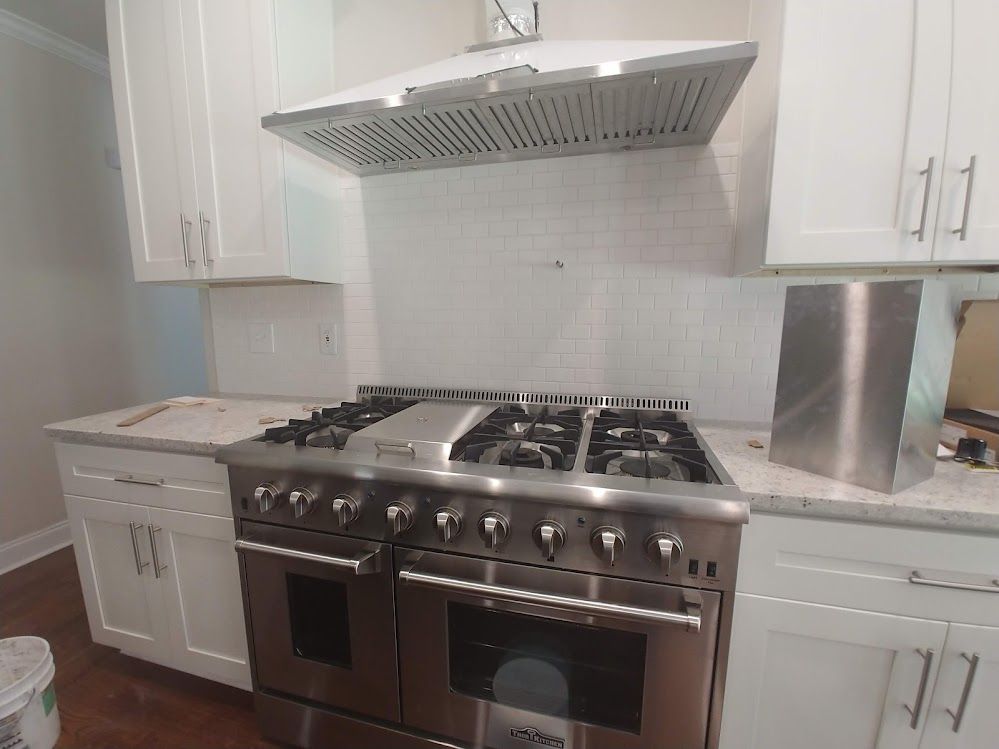 A kitchen with stainless steel appliances and white cabinets.