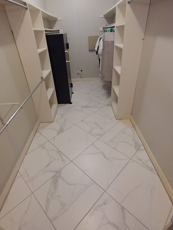 A walk in closet with white tile floors and shelves.