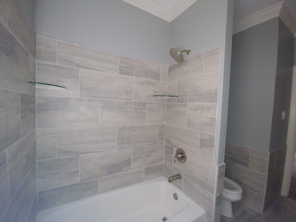 A bathroom with a bathtub , toilet and shower.