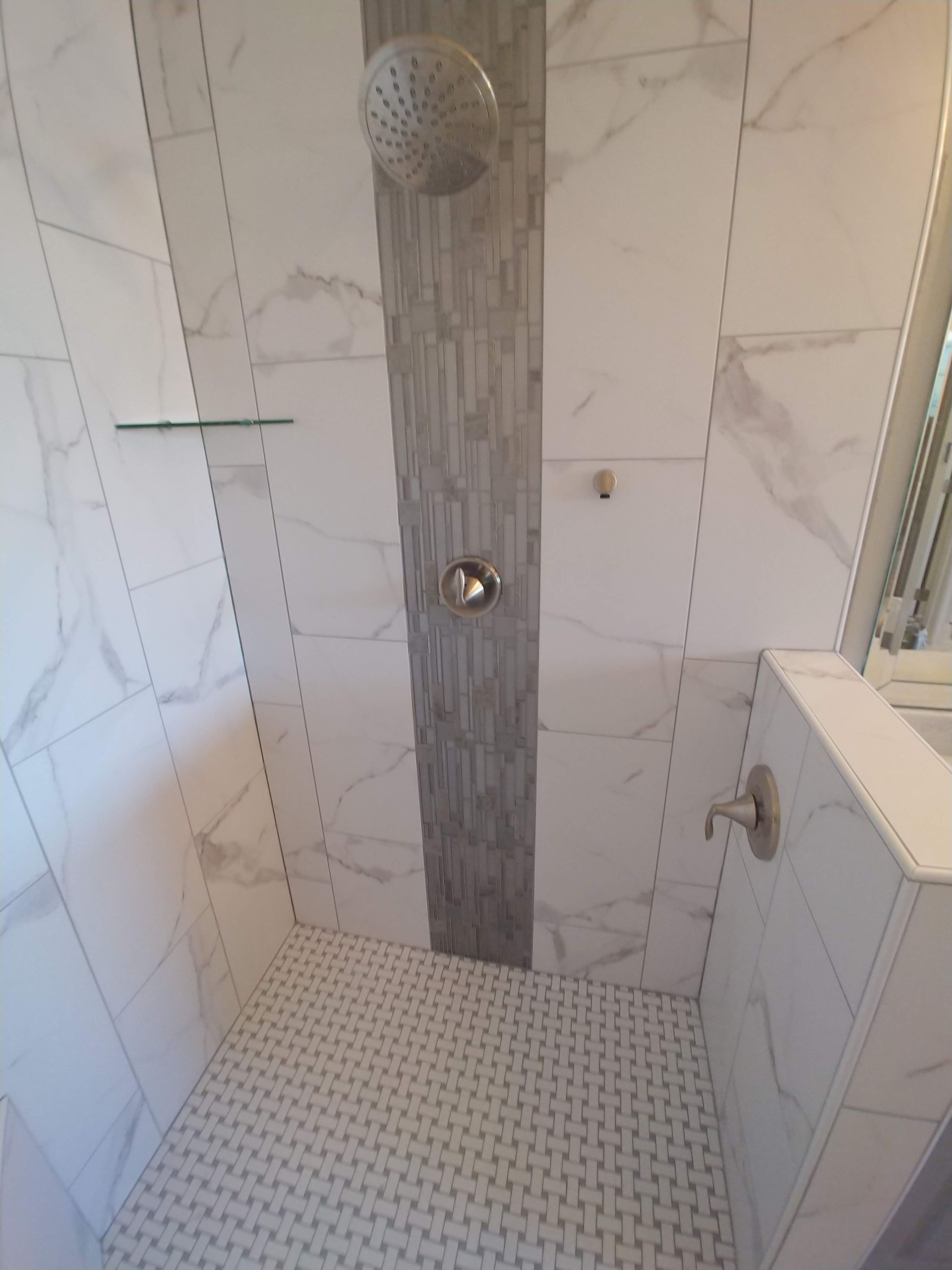 A bathroom with marble tiles and a walk in shower.