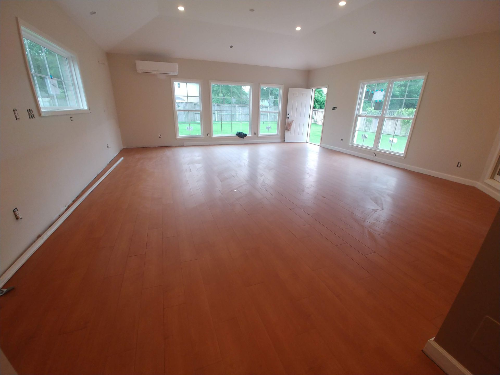 A large empty room with hardwood floors and lots of windows.