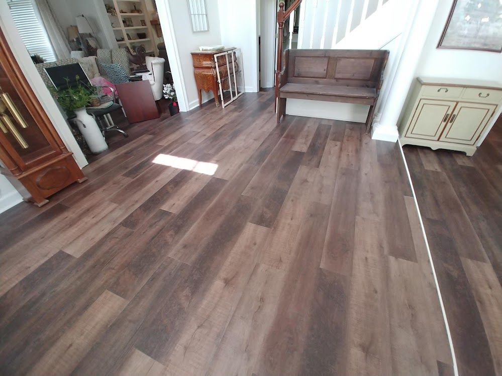 A wooden floor in a living room with a bench and stairs.