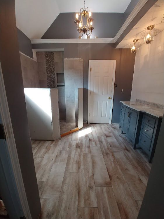 A bathroom with hardwood floors and a chandelier.