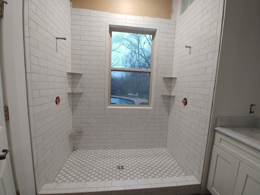 A bathroom with shower stall and a window.