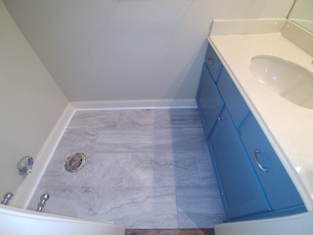 A bathroom with blue cabinets , a sink , and a bathtub.