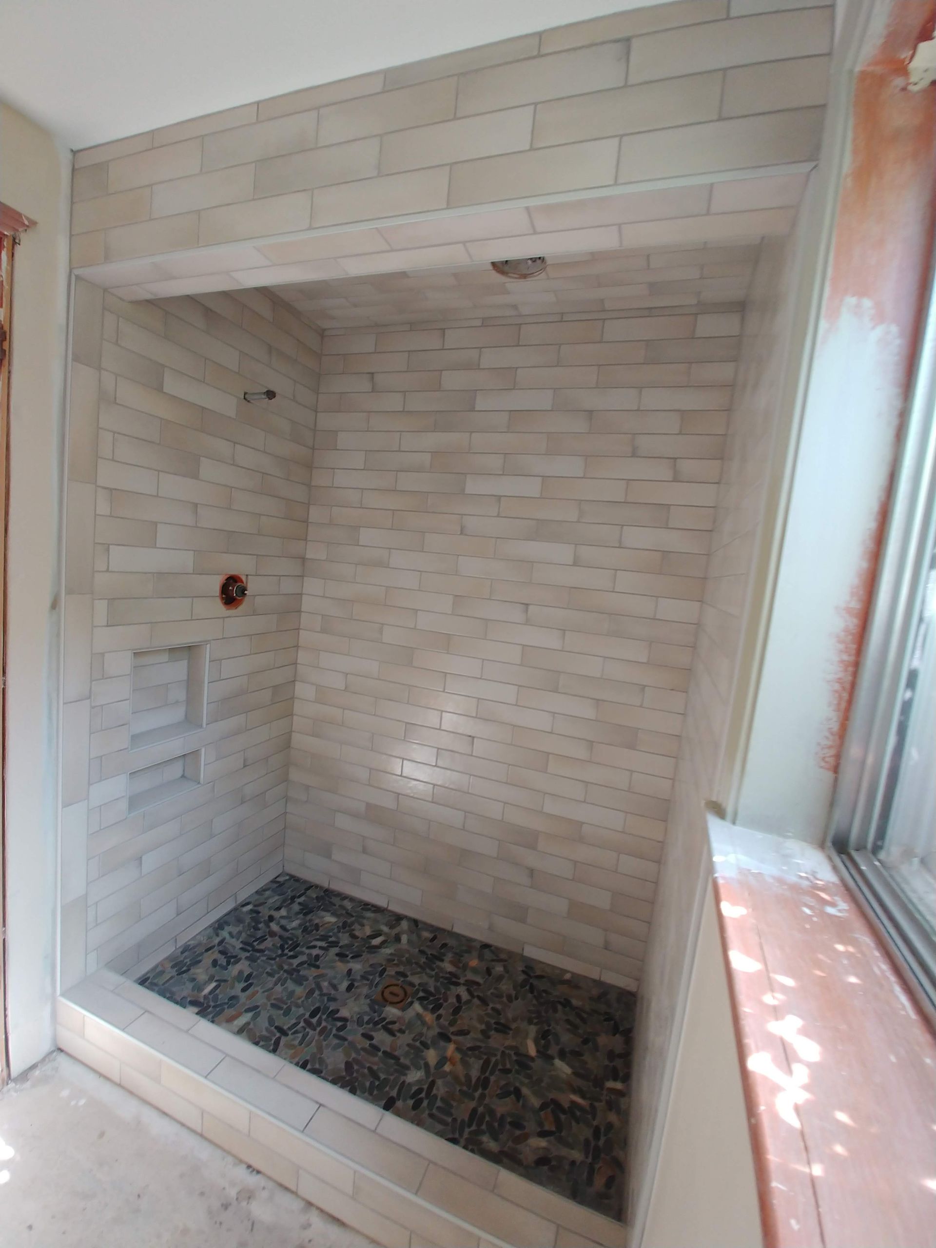 A bathroom with a walk in shower and a window.