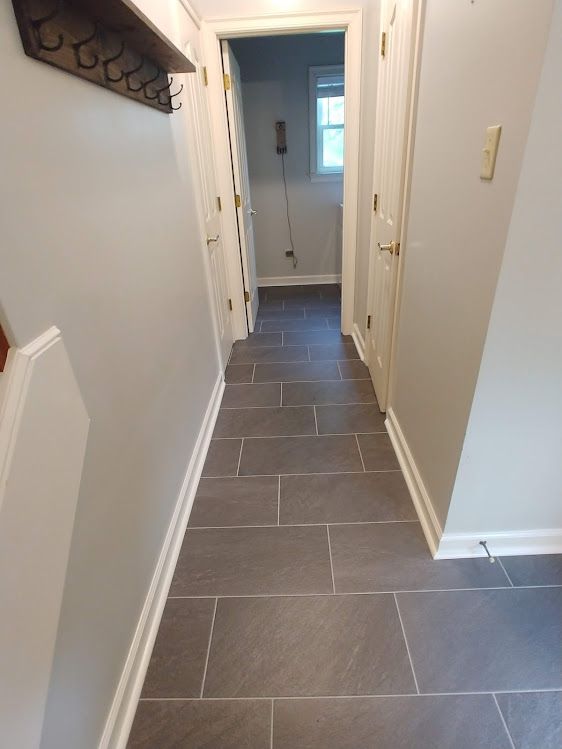 A hallway with a gray tile floor and white walls