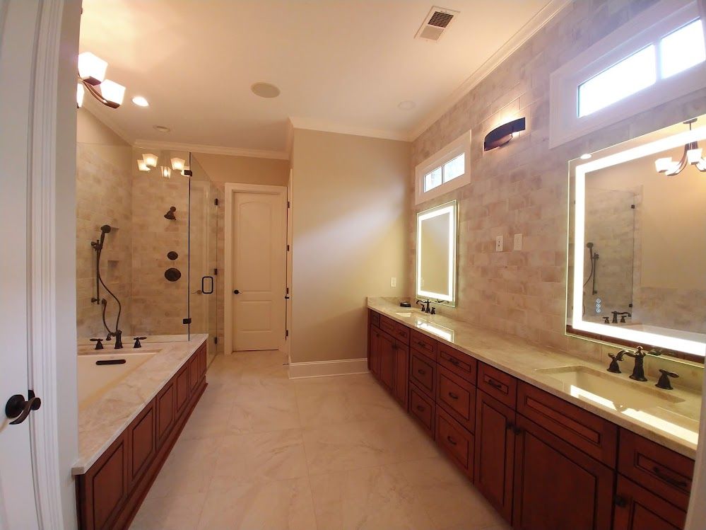 A bathroom with two sinks , a tub , and two mirrors.