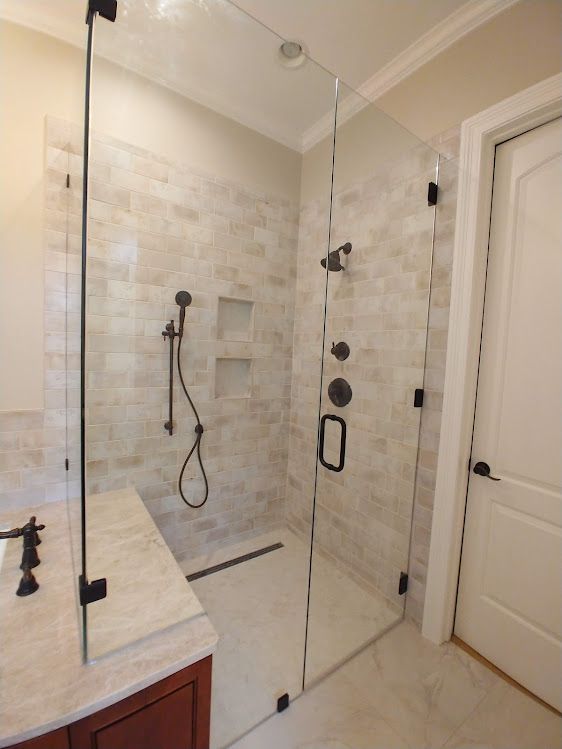 A bathroom with a walk in shower with a glass door