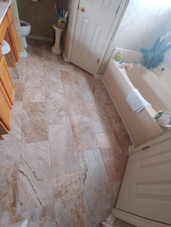 A bathroom with a bathtub , sink , toilet and tile floor.