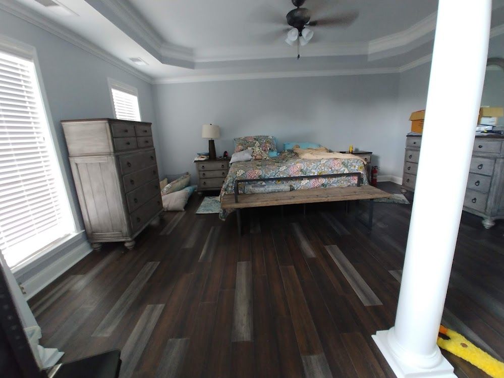 A bedroom with a bed , dresser , nightstand and a ceiling fan.