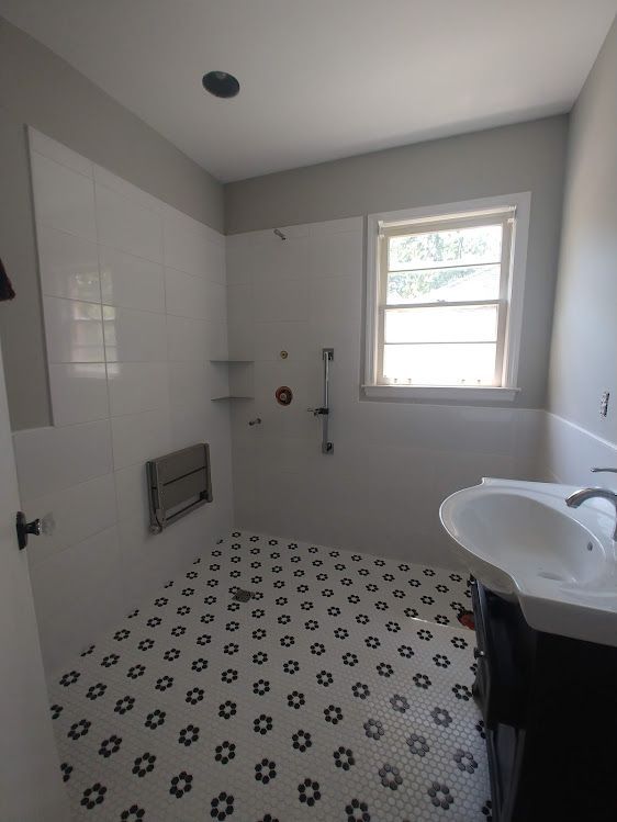 A bathroom with a sink a shower and a window