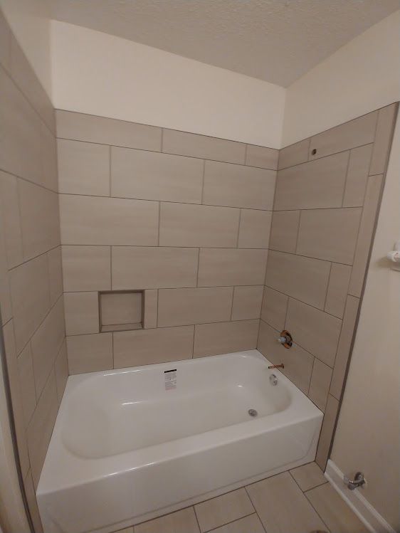 A bathroom with a bathtub and tiled walls.
