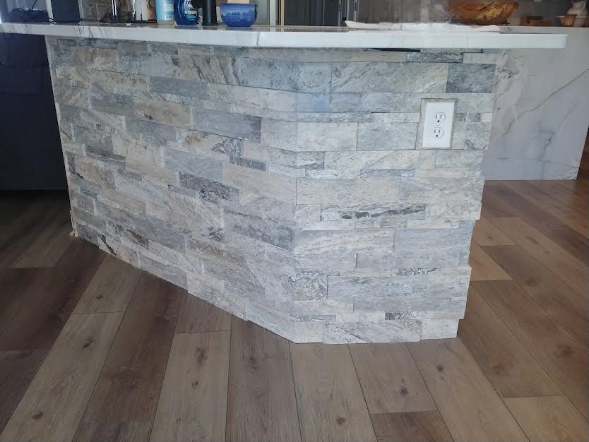 A kitchen island with a brick wall and a wooden floor.