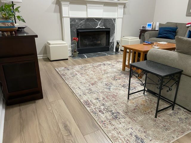 A living room with a fireplace , couch , table and rug.
