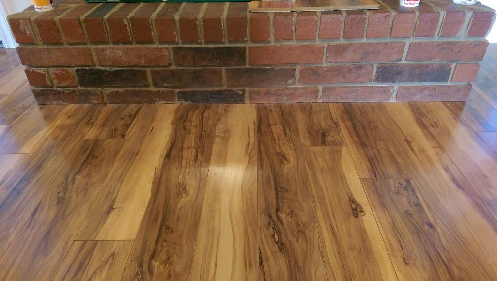 A wooden floor with a brick fireplace in the background.