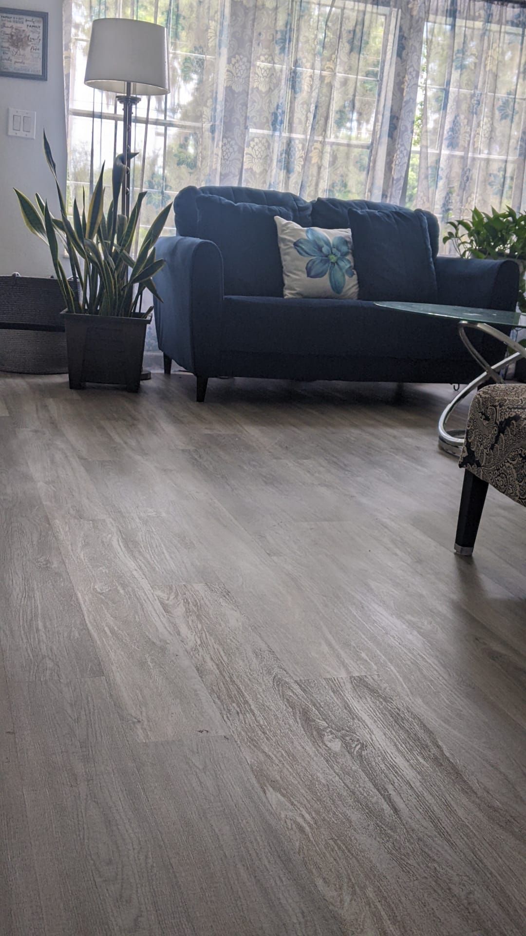 A living room with a couch , chair , table , lamp and potted plants.