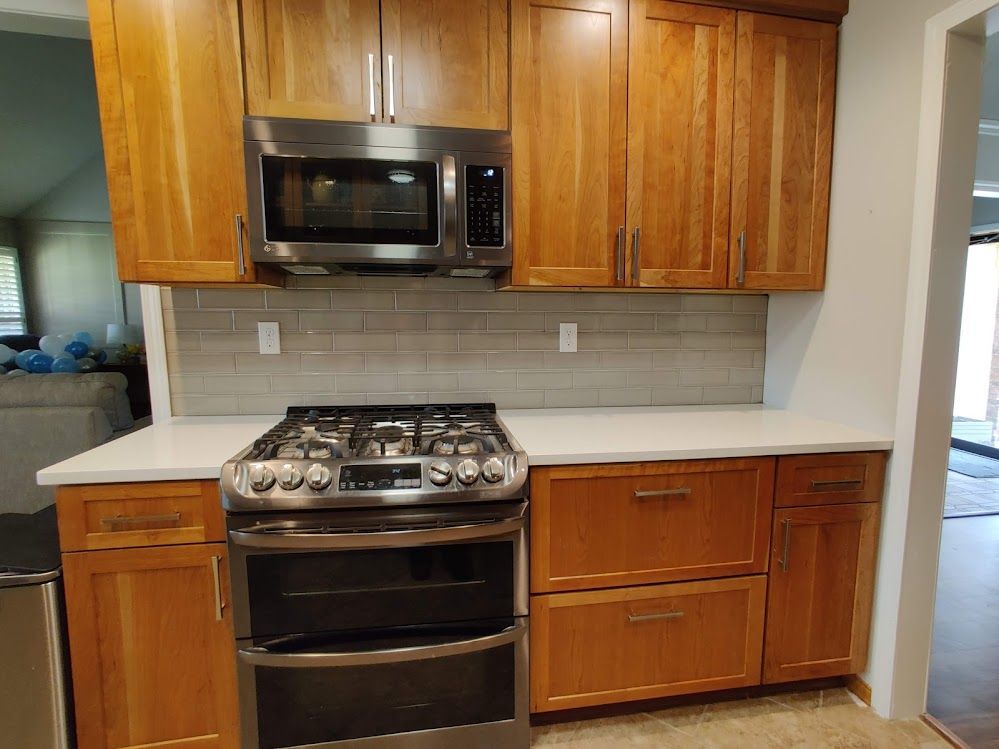 A kitchen with wooden cabinets , a stove and a microwave.