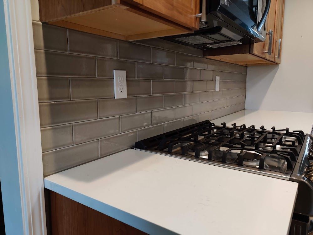 A kitchen with a stove top oven and a microwave with brick backsplash.