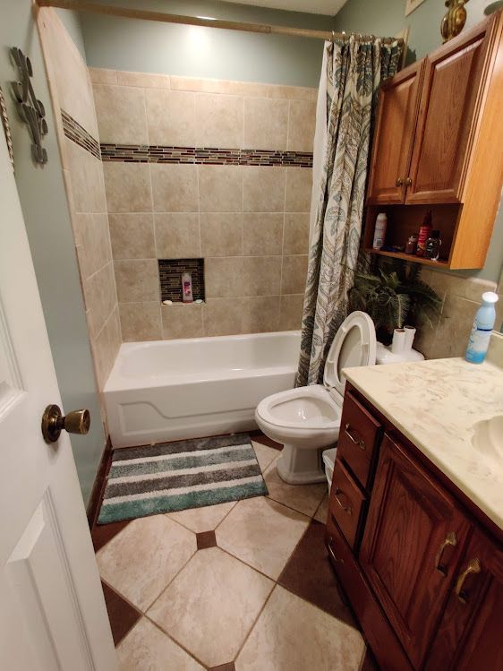 A bathroom with a tub , toilet , sink and cabinets.
