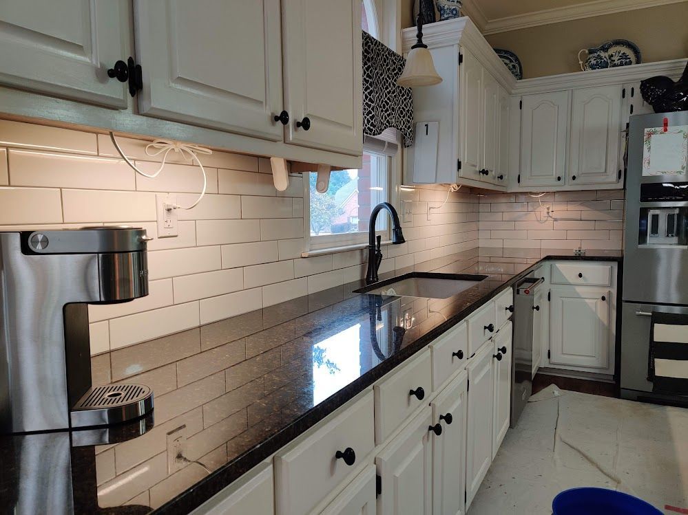 A kitchen with white cabinets and black counter tops