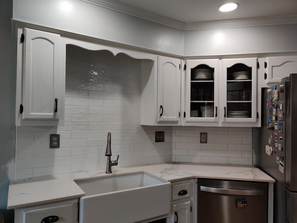 A kitchen with white cabinets , a sink , a refrigerator , and a dishwasher.