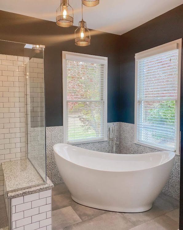 A bathroom with a tub , shower , and two windows.