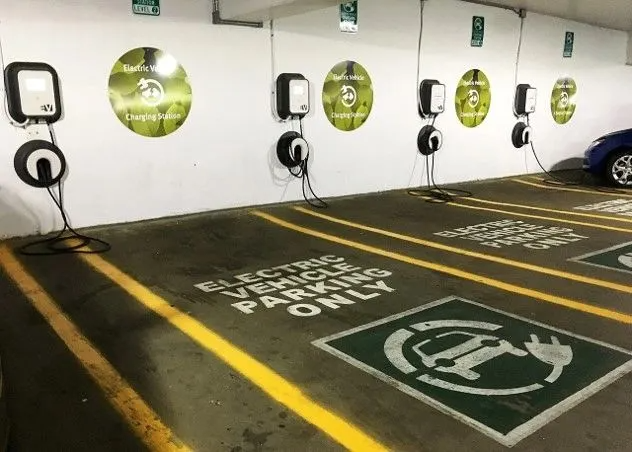 Electric vehicle charging stations in parking garage, marked with signage and painted parking spaces.
