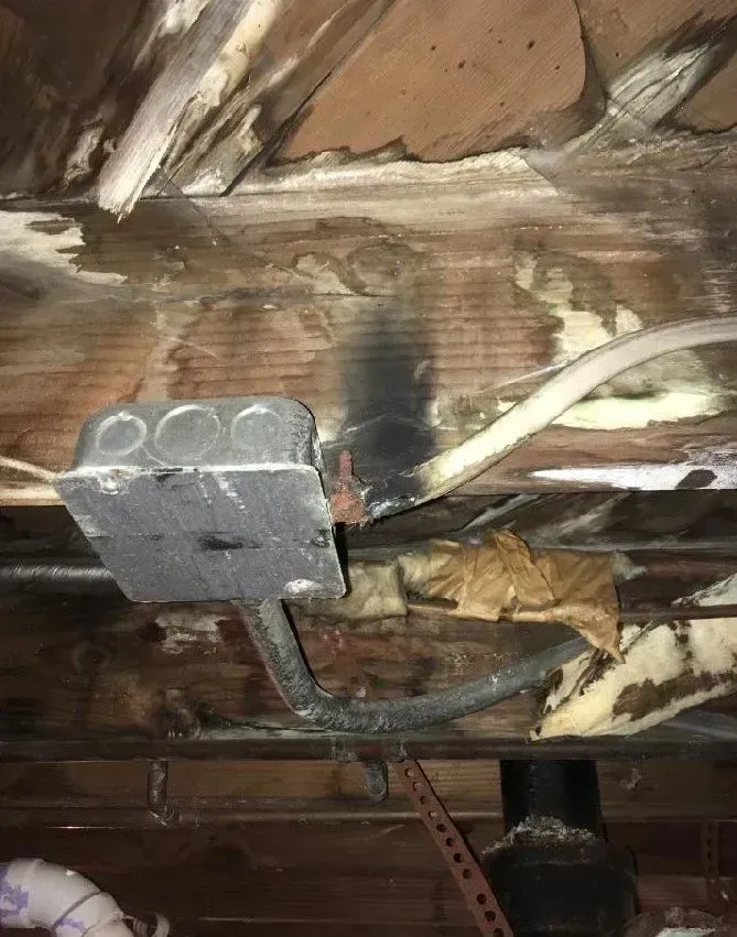 Damaged ceiling with electrical box, charred wood, exposed wires, and possible water damage.