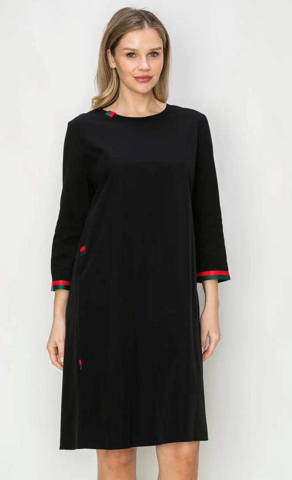 Woman wearing a black dress with red trim, standing indoors, facing forward.