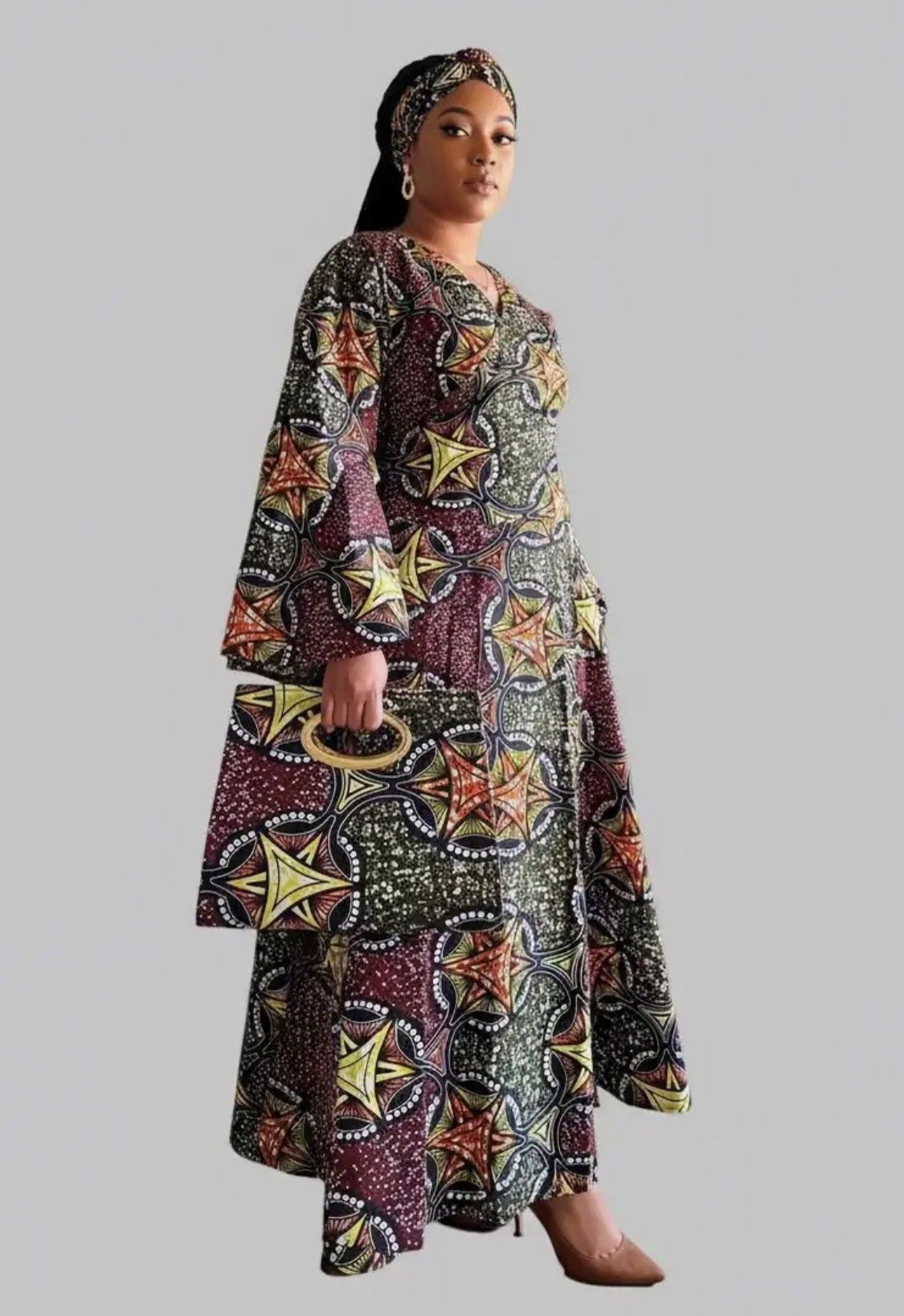 Woman in a long, patterned dress and matching headband, holding a clutch.