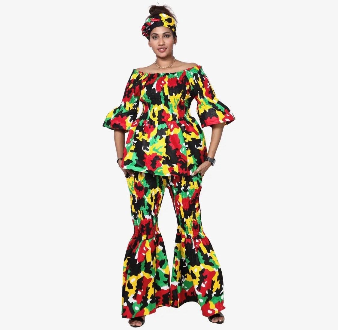 Woman in colorful patterned African print outfit, off-shoulder top, flared pants, matching head wrap.