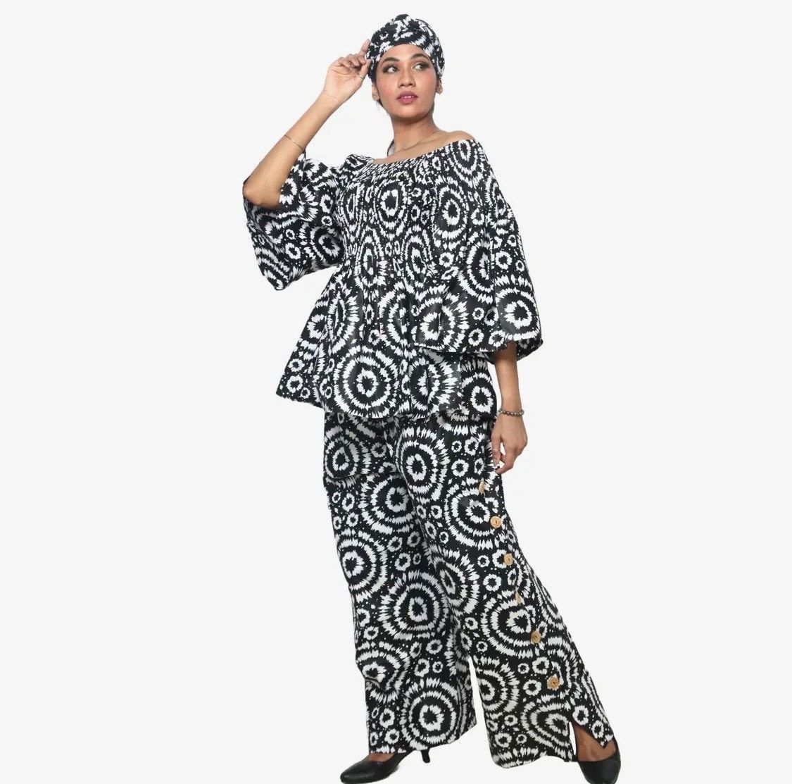 Woman in black and white patterned African-style outfit, includes head wrap, top, and pants.
