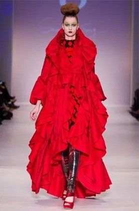 A woman is walking down a runway wearing a red dress with ruffles