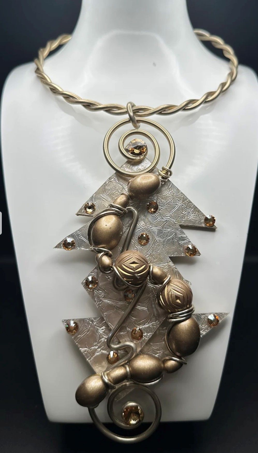 A necklace with a tree shaped pendant is on a mannequin