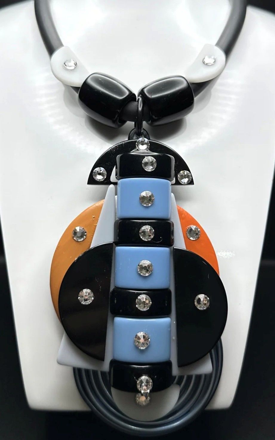 A necklace with a pendant that looks like a tie is on a mannequin