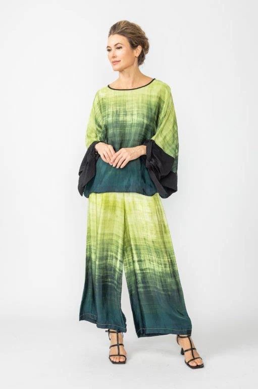 A woman is wearing a green and black tie dye top and wide leg pants