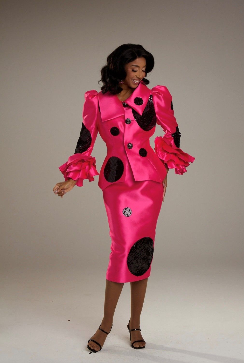 A woman is wearing a pink dress with black polka dots on the sleeves