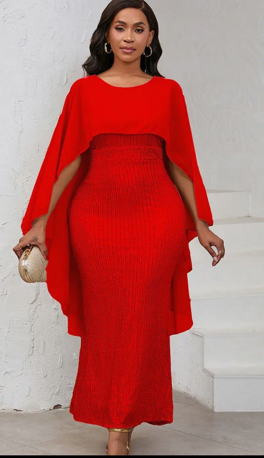 A woman is wearing a red dress with a cape on the sleeves