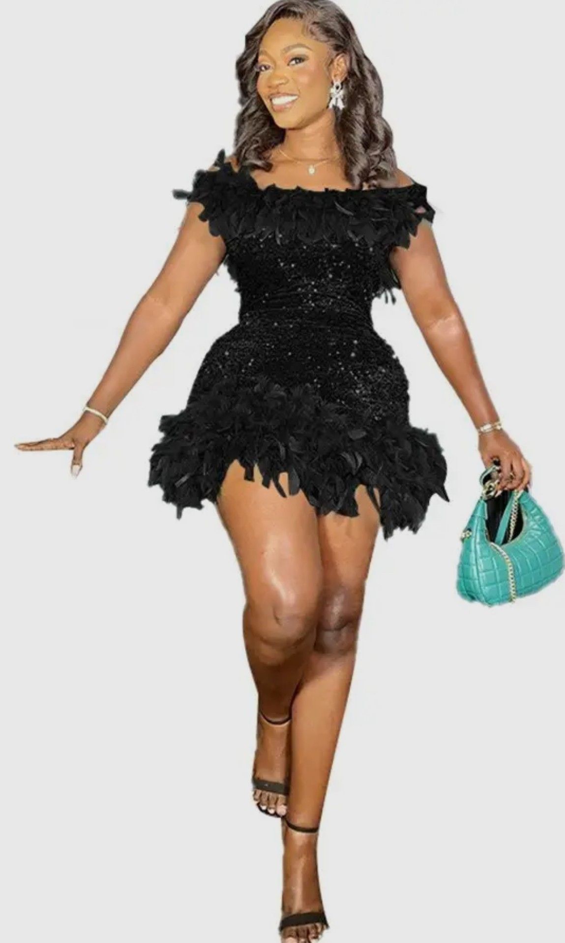 A woman in a black dress is holding a green purse