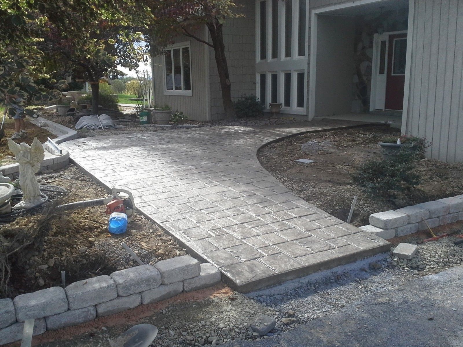 Brick pathway leading to a house entrance, bordered by low brick walls and landscaping.